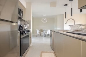 Eine moderne Küche mit Edelstahlgeräten, einem Essbereich mit weißen Stühlen und einem minimalistischen Design.