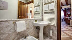 A bathroom with a marble sink, a mirror, a towel rack with towels, and a wooden door. - ANGELS' HOUSE (Venezia)