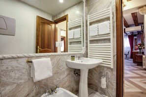A bathroom with a marble sink, a mirror, a towel rack with towels, and a wooden door. - ANGELS' HOUSE (Venezia)