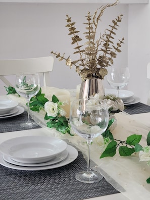 A dining table set with white plates, clear wine glasses, and a decorative vase with gold foliage. - Birmingham Contractor Stay, 5 Bed, Private Parking, Near M6, Groups (Birmingham)