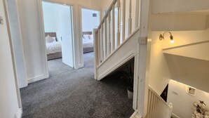 A staircase leading to a bedroom with a bed, a potted plant, and a wall-mounted light fixture. - Birmingham Contractor Stay, 5 Bed, Private Parking, Near M6, Groups (Birmingham)