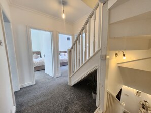 A staircase leading to a bedroom with a bed, a potted plant, and a wall-mounted light fixture. - Birmingham Contractor Stay, 5 Bed, Private Parking, Near M6, Groups (Birmingham)