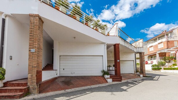 A residential building with a white garage door, a brick column, and a balcony with railings. - Tranquility Villa With Pool Private Garden BBQ (Farkë)