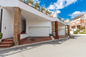 A residential building with a white garage door, a brick column, and a balcony with railings. - Tranquility Villa With Pool Private Garden BBQ (Farkë)
