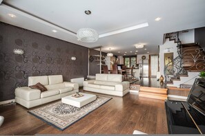 Ein modernes Wohnzimmer mit einem Klavier, zwei Sofas, einem Couchtisch und einem gemusterten Teppich.