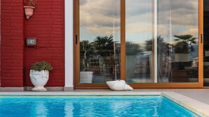 A swimming pool with a red brick wall, a large glass door, and a white shell decoration. - Tranquility Villa With Pool Private Garden BBQ (Farkë)