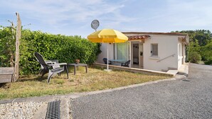 A small house with a patio, a yellow umbrella, and a satellite dish. - Bed and Breakfast 'Chambre Bleue' with Private Garden, Wi-Fi and Air Conditioning (Saint Aulaye-Puymangou)