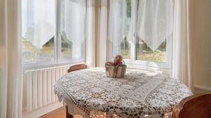 A room with a round table, a chair, a window with curtains, and a view of greenery outside. - Bed and Breakfast 'Chambre Bleue' with Private Garden, Wi-Fi and Air Conditioning (Saint Aulaye-Puymangou)