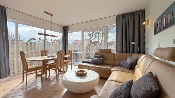 En rummelig opholdsstue med sofa, sofabord og spiseplads.