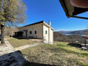 A single-story building with a flat roof, a small porch, and a view of a lake and mountains.
