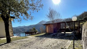 A rustic cabin with a stone wall, a wooden deck, and a view of mountains and a lake. - Casale Nelli - Window on the Lake (Petrella Salto)
