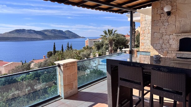A balcony with a view of the sea, a stone wall, and a grill area. - Villa Maria Peninsula (Kas)