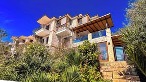 A multi-story house with a stone facade, multiple balconies, and a wooden pergola. - Villa Maria Peninsula (Kas)