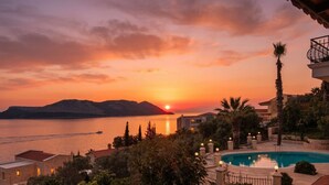 A resort with a swimming pool, a view of the sunset over water, and a mountainous backdrop. - Villa Maria Peninsula (Kas)