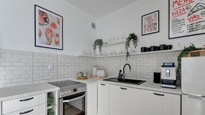 Una cocina moderna con armarios blancos, horno integrado, cafetera y fregadero.