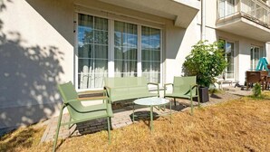 Un edificio con un patio amoblado, con muebles de exterior y una planta en maceta.