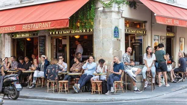 Un restaurante con mesas al aire libre, un toldo rojo y un letrero que dice 'SAINT GERVAIS'.