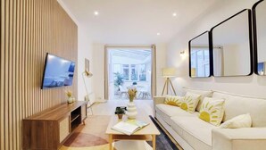 Una sala moderna con televisor, sofá y comedor con mesa y sillas.