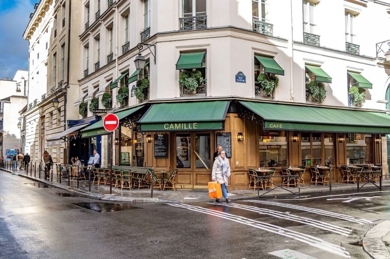 A building with a green awning labeled 'CAMILLE' and outdoor seating.