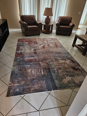 A living room with two leather armchairs, a patterned rug, and a lamp on a side table. - Enjoyable 3-bedroom house with AC in quaint Sun City West +55 community. (Sun City West)
