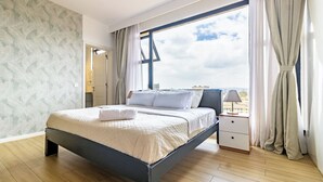 Ein modernes Schlafzimmer mit einem Bett, einem Nachttisch, einem Fenster mit Vorhängen und Blick auf die Stadt.