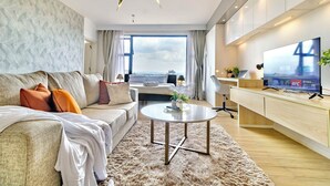 Ein modernes Wohnzimmer mit einer Couch, einem Couchtisch, einem Fernseher und Blick auf die Stadt.