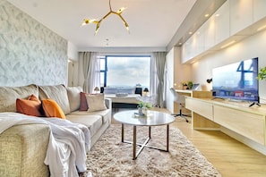 A modern living room with a sofa, coffee table, TV, and a view of the city. - Stunning studio with city views steps from the Junction Mall (Nairobi)