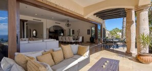 A spacious living area with a sofa, dining area, and a view of the ocean. - Luxury 5BD With Stunning Ocean View - Casa Jalisco (San José del Cabo)