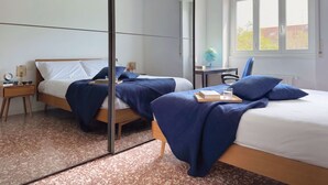 A modern hotel room with two beds, a large mirror, a desk with a globe, and a window with a view of the outside. - Casa Paolo Retro-design With Balcony Near Metro (Milan)