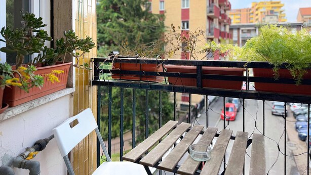 A balcony with potted plants, a small table, and a railing. - Casa Paolo Retro-design With Balcony Near Metro (Milan)
