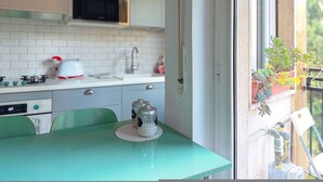 A kitchen with a microwave, stove, and cabinets. There is a window with a view of greenery. - Casa Paolo Retro-design With Balcony Near Metro (Milan)