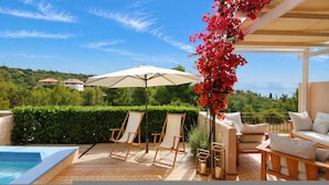 Un espace aménagé au bord de la piscine, avec des chaises longues, une table et un grand parasol.