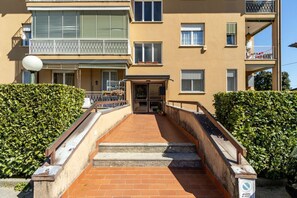 Un edificio de varios pisos con una entrada central, escalones que la conducen y un balcón en el piso superior.