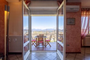 Una habitación con puerta de vidrio corrediza que da a un balcón con mesa y sillas.
