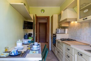 Cocina compacta con microondas, estufa y comedor con mesa para dos.