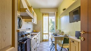 Eine kompakte Küche mit Essbereich, einem an der Wand befestigten Fernseher und einer Glastür zum Balkon.