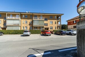 Ein mehrgeschossiges Wohngebäude mit Balkonen, geparkten Autos und blauem Himmel.