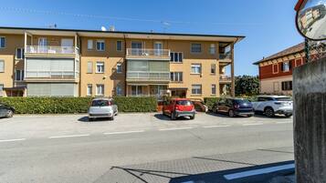 Un edificio residenziale a più piani con balconi, auto parcheggiate e cielo sereno.