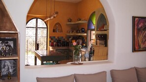 A cozy living room with a large arched window overlooking a kitchen. - Villa Nouran (Ghazoua)