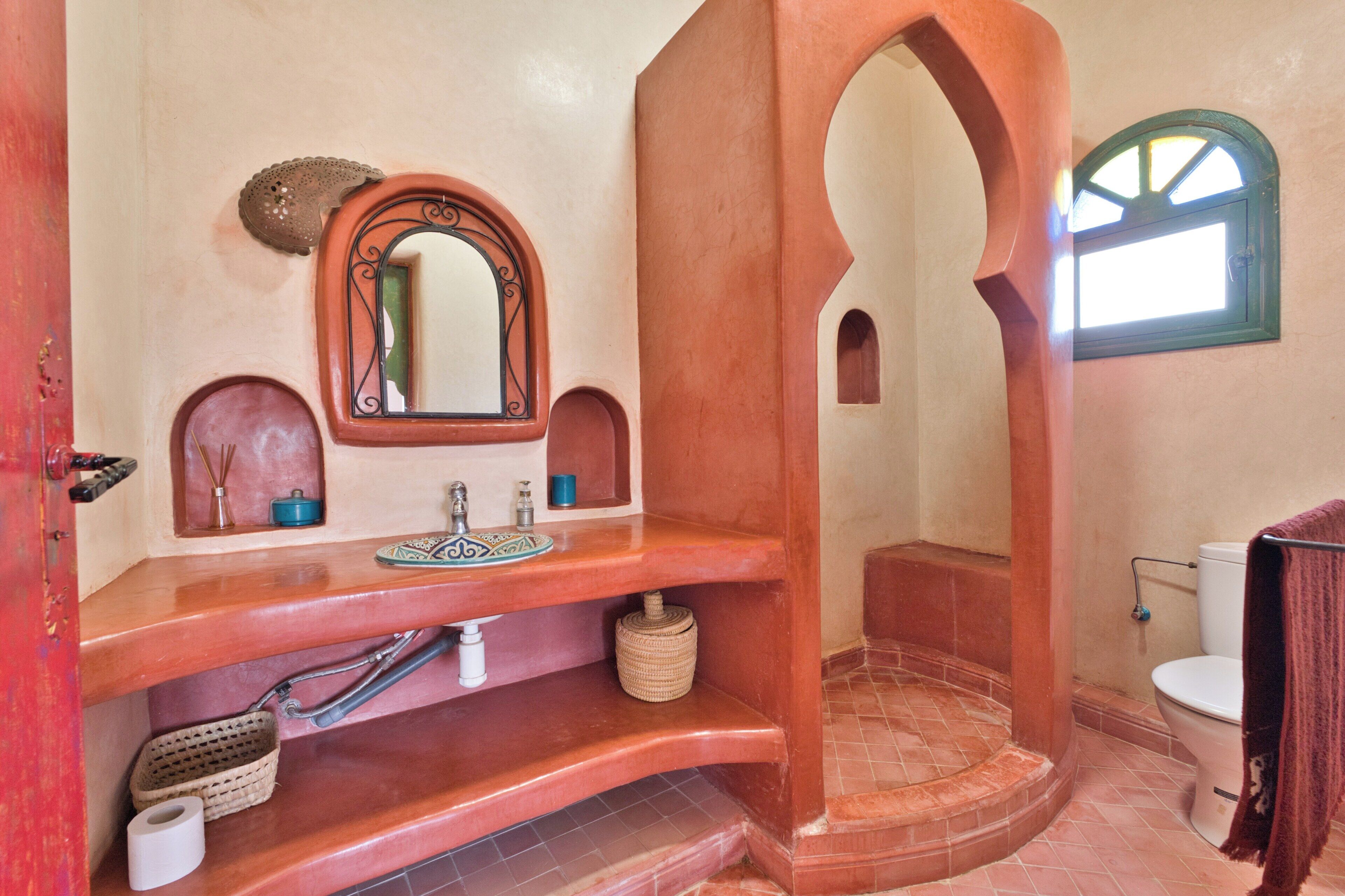 Un baño con un lavamanos curvo, un espejo, una ventana pequeña y un inodoro.