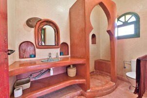 Un baño con un lavamanos curvo, un espejo, una ventana pequeña y un inodoro.