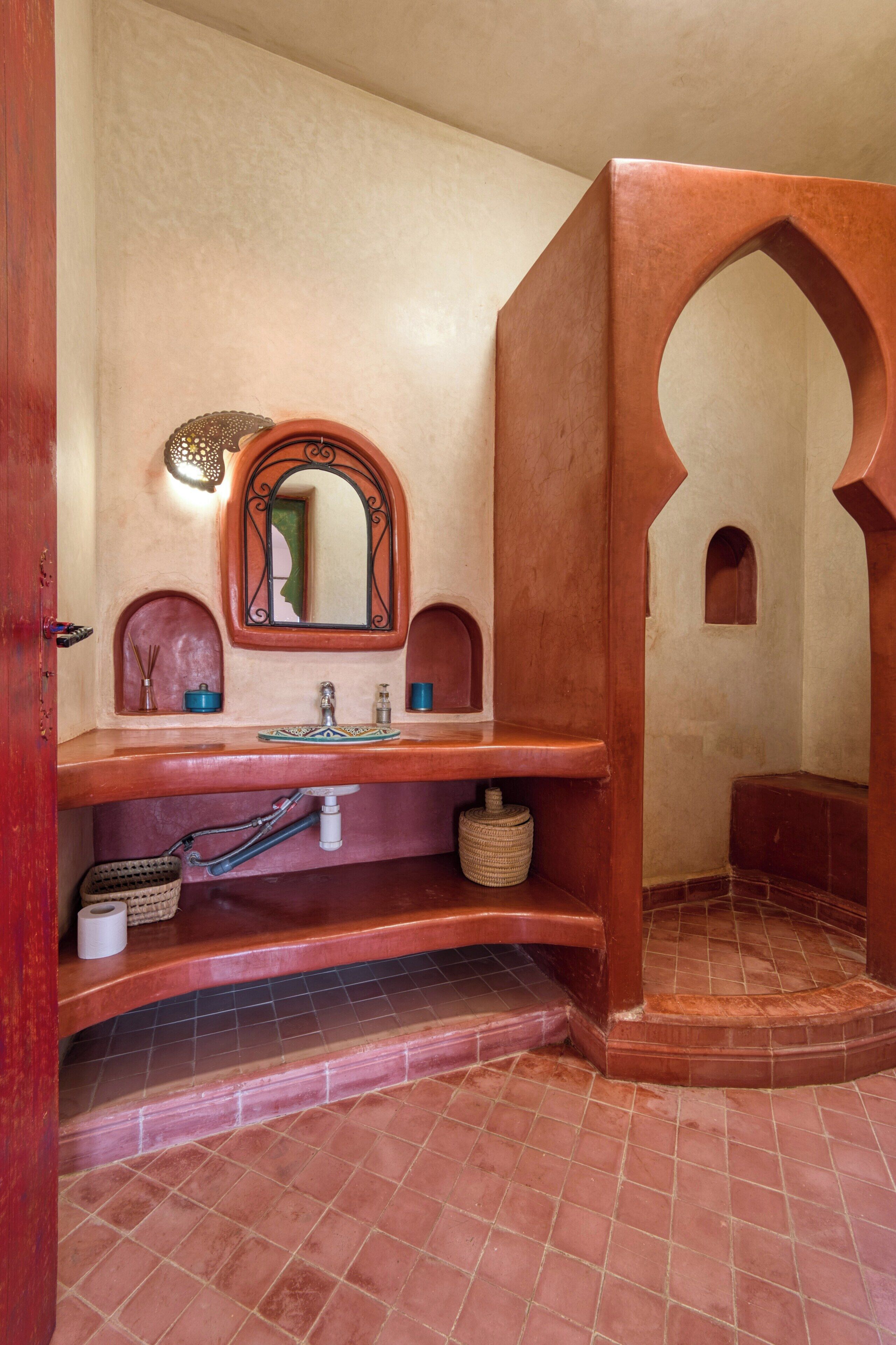 A bathroom with a wooden vanity, a mirror, and a tiled floor.