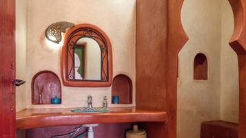 A bathroom with a wooden vanity, a mirror, and a tiled floor.