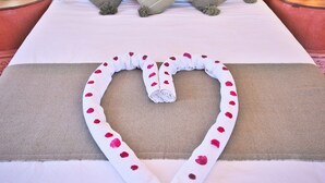 A bed with a heart-shaped towel arrangement, two pillows, and a nightstand with a lamp. - Villa Nouran (Ghazoua)