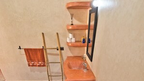 A bathroom with a large, terracotta-colored bathtub, a wooden ladder, a towel rack, and a mirror. - Villa Nouran (Ghazoua)