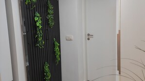 Un pasillo con un panel vertical negro, una puerta blanca y suelo de madera.