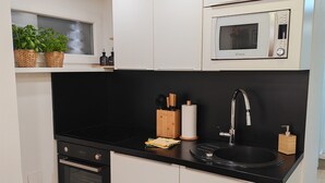 Una cocina moderna con armarios blancos, encimera negra, microondas integrado, un lavamanos y una estufa.