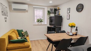 Una sala de estar moderna con un sofá, una mesa de comedor con sillas, un televisor y un reloj en la pared.