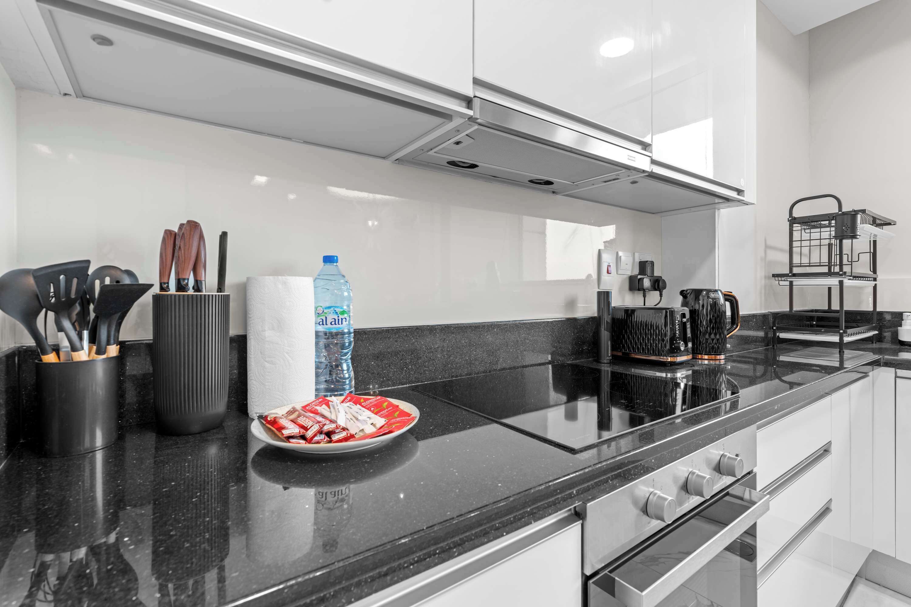 A modern kitchen with a black countertop, stainless steel appliances, and a water dispenser.