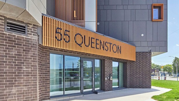 A modern building with a sign reading '55 QUENSTON' and a brick facade.